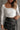 Close front view of model wearing the Greta Ivory Basic Long Sleeve Crop Top that has ivory knit fabric, a cropped waist, a thick band hem, a square neckline and long sleeves.