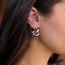 Side view of model wearing the Mallory Red & Green Hoop Earrings that feature small open hoops with red, white and green stripes with gold details.