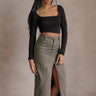 Full body front view of model wearing the Greta Black Basic Long Sleeve Crop Top that has black knit fabric, a cropped waist, a thick band hem, a square neckline, and long sleeves.