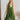 Frontal view of the Falling Flowers Dress that features a moss green material, a deep V neckline, a sleeveless design with thick straps, a side ruffle detail, a lettuce edge bottom hem, a V back, a flowy fit, and a mini length
