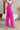 Side view of model wearing the Make A Statement Pants, which feature a pink chiffon material, a high-rise fit, a thick waist band, a wide leg fit, and a back zipper closure