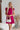 Frontal view of the Perfect Pair Dress that features a magenta material, a high rounded neckline with a ruffle detail, a short ruffle sleeve, a pleated top, a tiered design, a back button closure, a flowy fit, and a mini length.