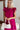 Frontal view of the Perfect Pair Dress that features a magenta material, a high rounded neckline with a ruffle detail, a short ruffle sleeve, a pleated top, a tiered design, a back button closure, a flowy fit, and a mini length.