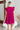 Back view of the Perfect Pair Dress that features a magenta material, a high rounded neckline with a ruffle detail, a short ruffle sleeve, a pleated top, a tiered design, a back button closure, a flowy fit, and a mini length.