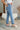 Side view of the Out With The Old Jeans that features a medium wash denim with distressing, a front button and zip closure, two front pockets, distressing at the knees and below, a frayed bottom hem, two back pockets, and a straight leg fit.