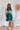 Frontal view of the Sweet Summer Romper that features a multi-colored design, a V neckline, a half cuffed sleeve, a three tiered design, two side pockets, a shorts lining, a V back with a tie detail, a flowy fit, and a mini length.