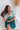 Frontal view of the Sweet Summer Romper that features a multi-colored design, a V neckline, a half cuffed sleeve, a three tiered design, two side pockets, a shorts lining, a V back with a tie detail, a flowy fit, and a mini length.
