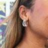 Side view of model wearing the Show Stopper Pearl Earring which features mini double hoops with white pearls and gold hardware.