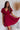 Frontal view of the All Things Nice Dress that features a red colored material, a V neckline, a short flowy sleeve, three buttons below the bust, an elastic waist, a V back with a tie closure, and a flowy fit.