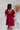 Back view of the All Things Nice Dress that features a red colored material, a V neckline, a short flowy sleeve, three buttons below the bust, an elastic waist, a V back with a tie closure, and a flowy fit.
