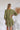 Back view of the Wish You Well Dress that features an olive gauze material, a frayed V neckline, a 3/4 sleeve, a button-up front, a tiered babydoll design, a flowy fit, and a mini length. 