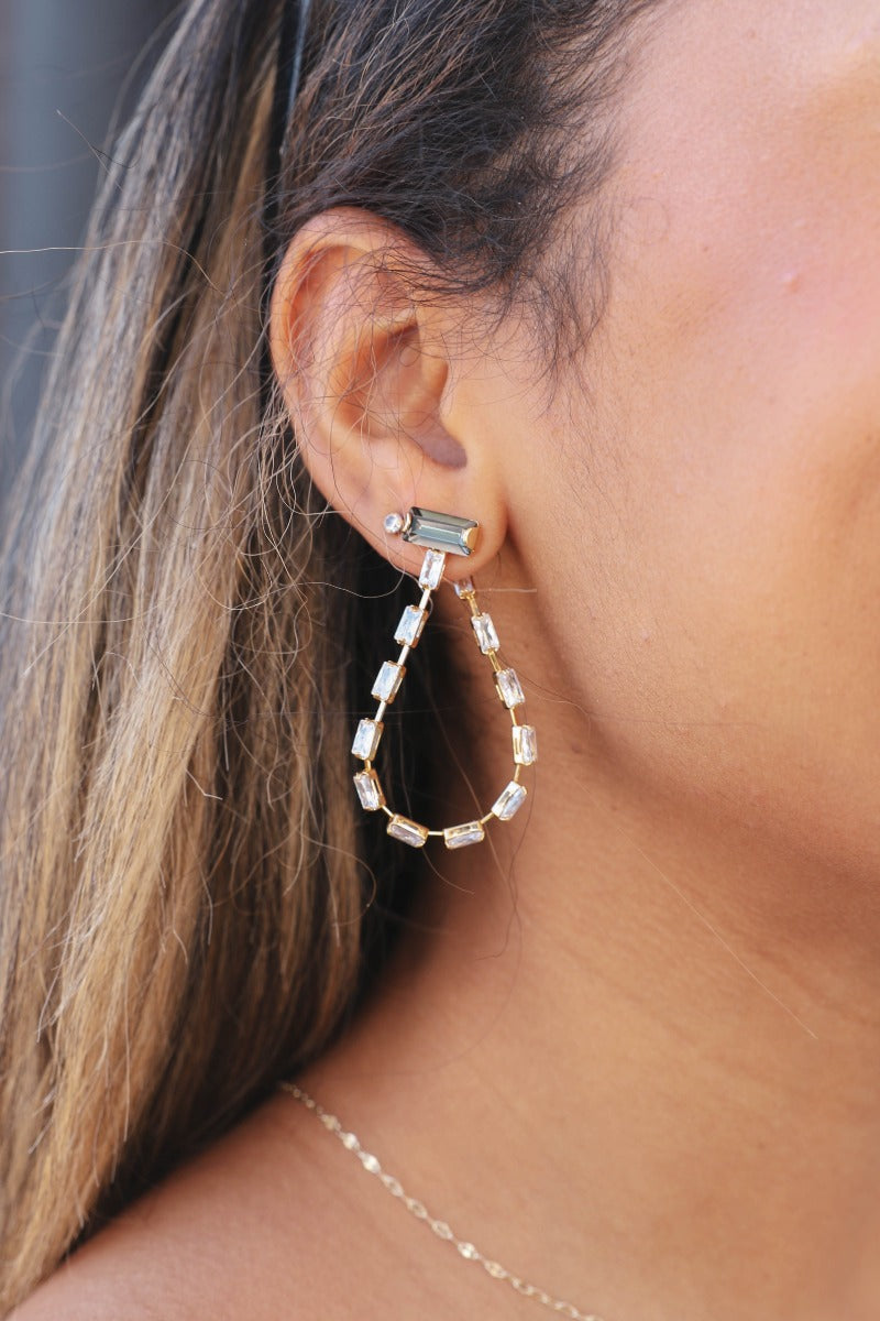 Side view of model wearing the Say You Love Me Earring  which features clear stones looped and two large grey stones set in gold.