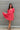 Frontal view of the Bubble Gum Mini Dress that features a pink cotton material, a squared neckline, a half sleeve, a tiered babydoll design, a back button closure, a flowy fit, and a mini length.