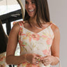 Front view of model wearing the It Must Be Love Top that has beige fabric with pink, yellow, and green floral print, a v-neckline, and tie straps.