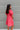 Back view of the Bubble Gum Mini Dress that features a pink cotton material, a squared neckline, a half sleeve, a tiered babydoll design, a back button closure, a flowy fit, and a mini length.
