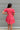 Back view of the Bubble Gum Mini Dress that features a pink cotton material, a squared neckline, a half sleeve, a tiered babydoll design, a back button closure, a flowy fit, and a mini length.