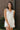 Front view of model wearing the Everlasting Bliss Romper that has white fabric, a pleated bottom with a lettuce hem, an elastic waist, a surplice neck with a tie and snap closure, and a keyhole back.