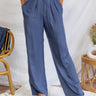 Frontal view of the On Your Mark Pants that features a blue satin material, a high-rise fit, a thick waist band, a clasp and zipper front closure, side pockets, a wide leg fit, and two back pockets.