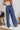 
Back view of the On Your Mark Pants that features a blue satin material, a high-rise fit, a thick waist band, a clasp and zipper front closure, side pockets, a wide leg fit, and two back pockets.
