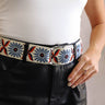 Close front view of model wearing the Celine Embroidered Floral Ring Belt that features beige fabric with blue, navy, and rust floral embroidery and a silver ring buckle.