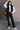 Full body view of model wearing the Sienna Black Sherpa Cropped Zip-Up Vest which features black suede and black sherpa fabric, two front pocket slits, front zip up, collared neckline, cropped waist and sleeveless.