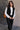 Front view of model wearing the Sienna Black Sherpa Cropped Zip-Up Vest which features black suede and black sherpa fabric, two front pocket slits, front zip up, collared neckline, cropped waist and sleeveless.