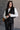 Front view of model wearing the Sienna Black Sherpa Cropped Zip-Up Vest which features black suede and black sherpa fabric, two front pocket slits, front zip up, collared neckline, cropped waist and sleeveless.
