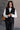 Front view of model wearing the Sienna Black Sherpa Cropped Zip-Up Vest which features black suede and black sherpa fabric, two front pocket slits, front zip up, collared neckline, cropped waist and sleeveless.