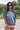 Front view of model wearing the Ford Graphic Tee that has dusty blue cotton fabric, round neckline and short sleeves. Graphic says "FORD" "MOTOR CO." "DETROIT" in white lettering. Graphic has a tire with wings in white. 
