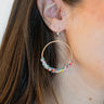  Side view of model wearing the Make It Fun Beaded Earrings which features gold closed hoops with multi, pastel color beads.