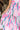 Close up view of model wearing the In My Favor Midi Dress which features a hot pink, light pink, green, blue and lavender color block pattern, tiered ruffle details, a pink skirt lining, a square neckline, adjustable straps, a smocked back, and a monochro