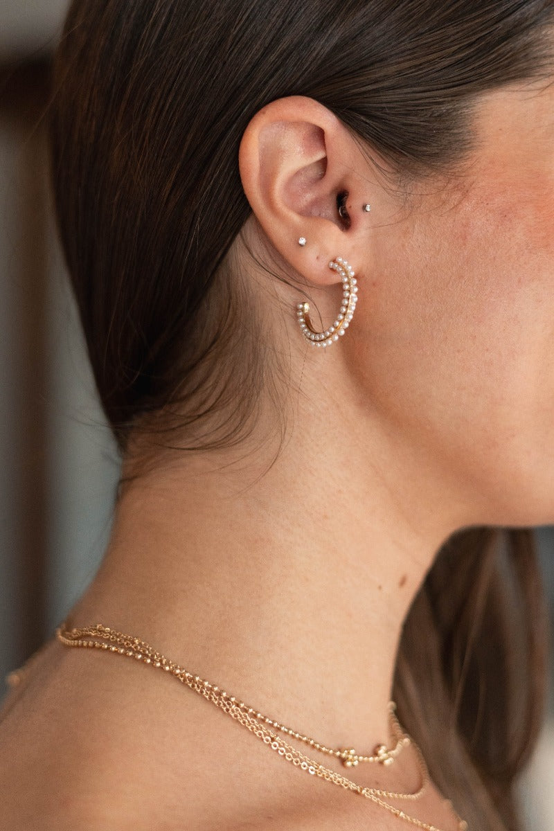 Side view of model wearing the Never Out Of Style Pearl Hoop which features medium, gold hoops with pearl details.