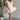 Full body front view of model wearing the One More Time Dress that has cream sheer fabric, a ruffled stripe design, a bubble hem, cream lining, a plunge neckline, ruffle straps, an open back and a monochromatic back zipper with a hook closure