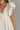 Close front view of model wearing the One More Time Dress that has cream sheer fabric, a ruffled stripe design, a bubble hem, cream lining, a plunge neckline, ruffle straps, an open back and a monochromatic back zipper with a hook closure