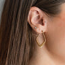 Side view of model wearing the Fall For You Earrings which features gold diamond shaped with gold rings.