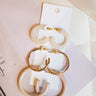 Ariel view of the High Class Earring Set in White which features a set of small cream hoops, gold medium hoops and tan large hoops.