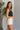 Side view of model wearing the Billie Cropped Denim Tank that has black acid wash fabric, a cropped waist, a square neckline, a sleeveless design, and a monochromatic back zipper with a hook closure.