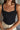 Close front view of model wearing the Billie Cropped Denim Tank that has black acid wash fabric, a cropped waist, a square neckline, a sleeveless design, and a monochromatic back zipper with a hook closure.