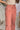 Close up view of model wearing the Street Views Cargo Pants which features mauve fabric, white contrast stitching, front pockets, side cargo pockets, back cargo pockets, a drawstring hem at the ankles, an elastic waistband with drawstring ties, and wide l