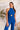 Upper front view of model wearing the Get On My Level Jumpsuit that has royal blue fabric, a front key hole , a halter neck with button closures, a sleeveless design, an open back, a back zipper with a hook closure, and flare pant legs.