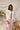 Front view of model wearing the Roxanne Rhinestone Fringe Jacket that has white denim fabric, a frayed hem, silver buttons, a collar, two front chest pockets with rhinestone fringe details, and long sleeves