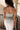 Back view of model wearing the Kora Olive Denim Strapless Peplum Top that has washed olive denim fabric, a peplum body, a sweetheart strapless neckline, and a back zipper with a hook closure.