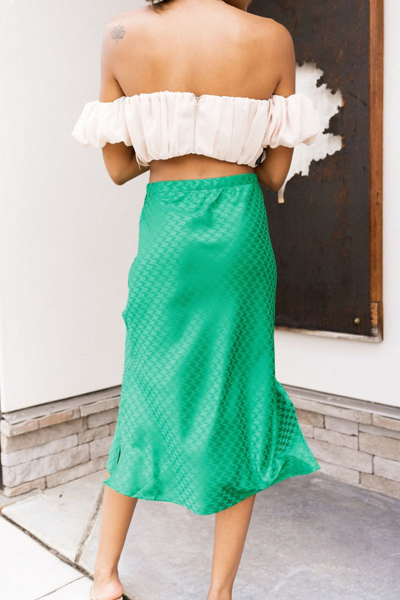 Back view of the Flow With Me Midi Skirt that features a green monochromatic houndstooth pattern, an elastic waistband, a side slit, and a midi length.