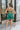 Back view of the Something Like That Dress that features a teal green satin material, a cowl neckline with cups at the bust, a sleeveless design with thin adjustable straps, a waist cut-out, an elastic waistline, and a criss-cross strap back