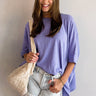 Front view of model wearing the Closet Classic Top which features lavender fabric, high-low hem, small slits on each side, round neckline, short sleeves and exterior lining details on the back.