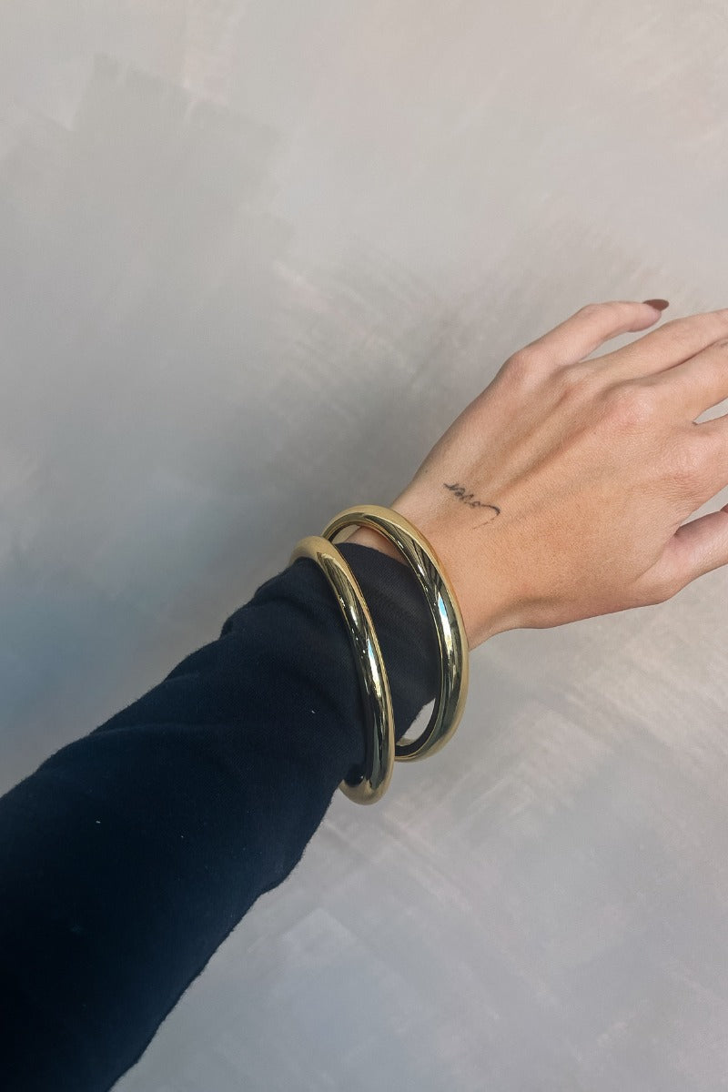Front view of model wearing the Ciara Gold Bangle Set which features two shiny gold bangles.