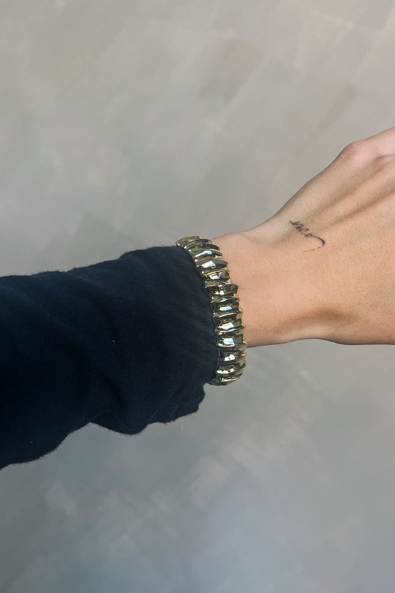 Close up view of model wearing the Maya Gold Groove Stretchy Bracelet which features gold, stretchy band with groove details.