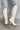 Back/ side view of the Going Places Boot that features a white colored western style boot, featuring a white leather upper, western inspired embroidery, an almond toe, a 2" stacked heel, pull-on tabs for easy entry, and a side zipper.