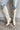 Frontal/ side view of the Going Places Boot that features a white colored western style boot, featuring a white leather upper, western inspired embroidery, an almond toe, a 2" stacked heel, pull-on tabs for easy entry, and a side zipper.