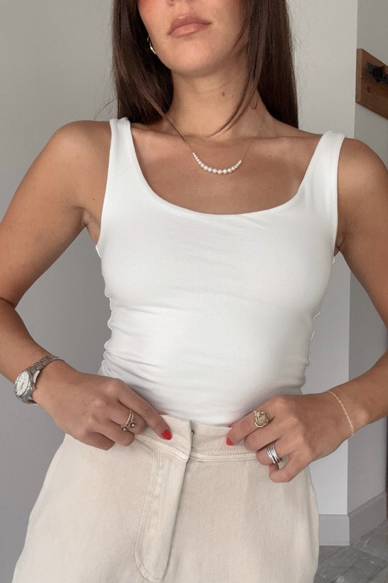 Front view of model wearing the Josie Off White Basic Scoop Neck Tank that has stretchy double-layered off white knit fabric, an elastic hem, a scooped neckline, and thick straps.